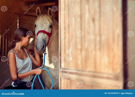 Teenage Girl Taking Care of Horse in Stable